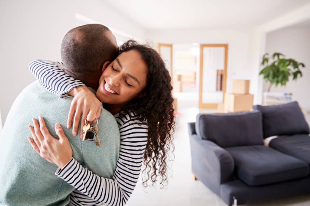 Loving Couple Hugging Holding Keys To New Home On Moving Day